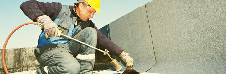 Roofer heating tar on a commercial roof