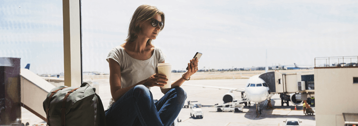 Woman In Airport On Phone Drinking Coffee